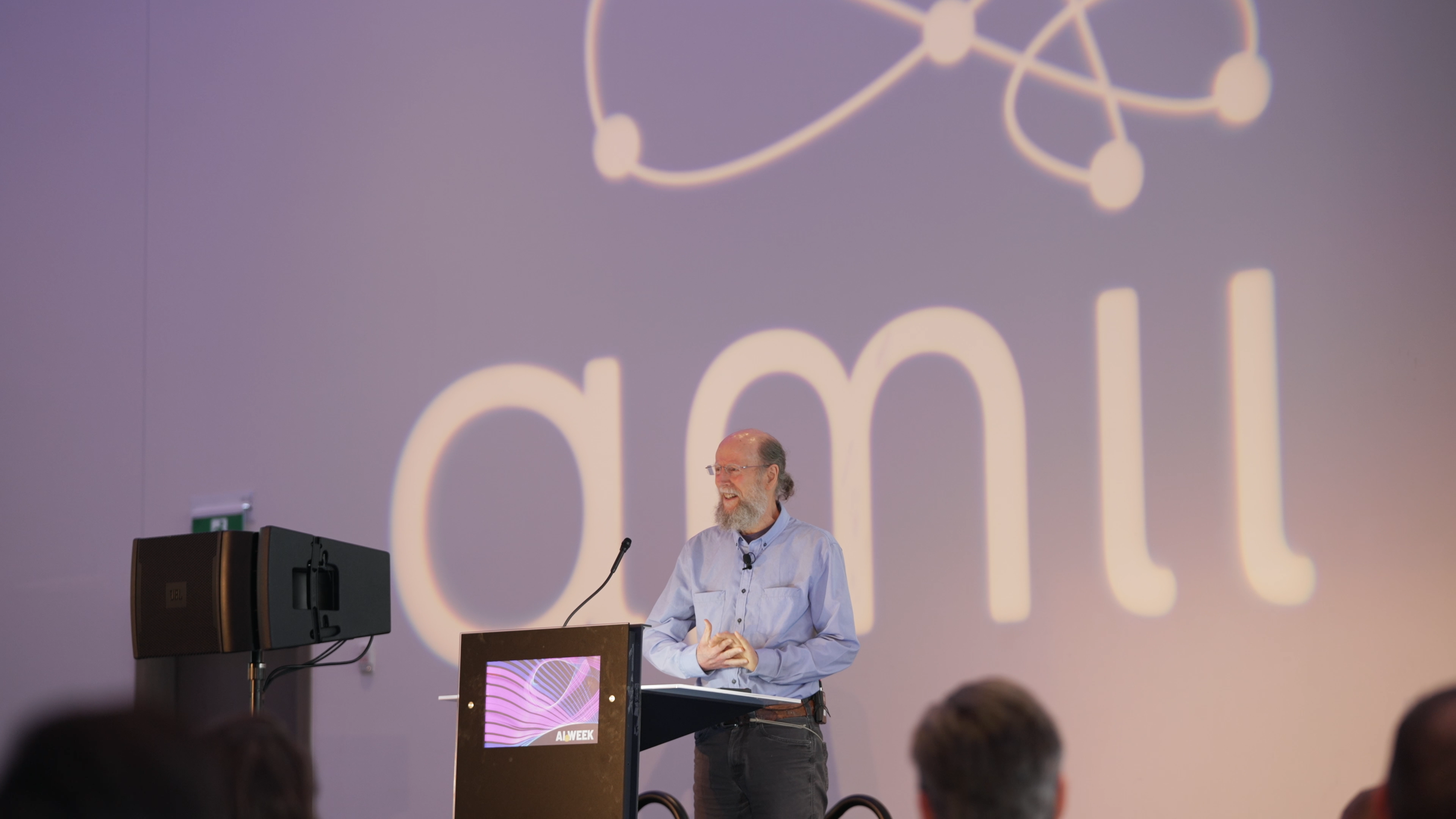 Rich Sutton on stage at a podium in from of the Amii logo