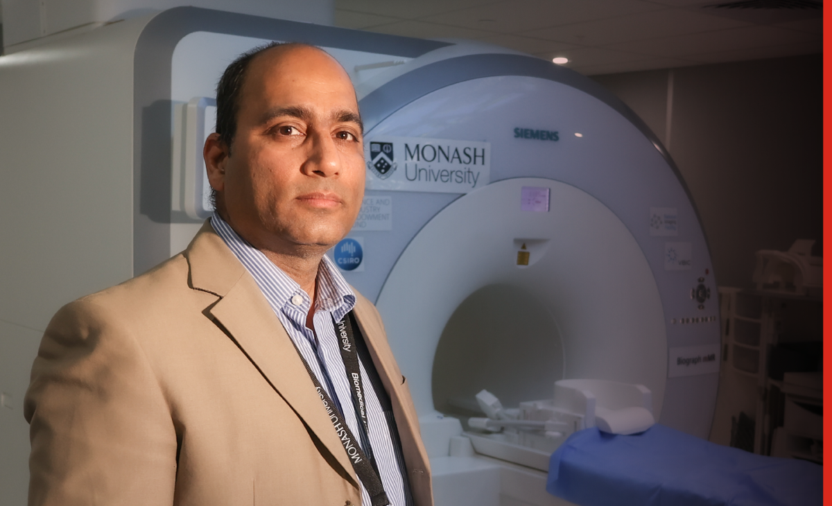 Photo of Adeel Razi in front of an MRI machine.